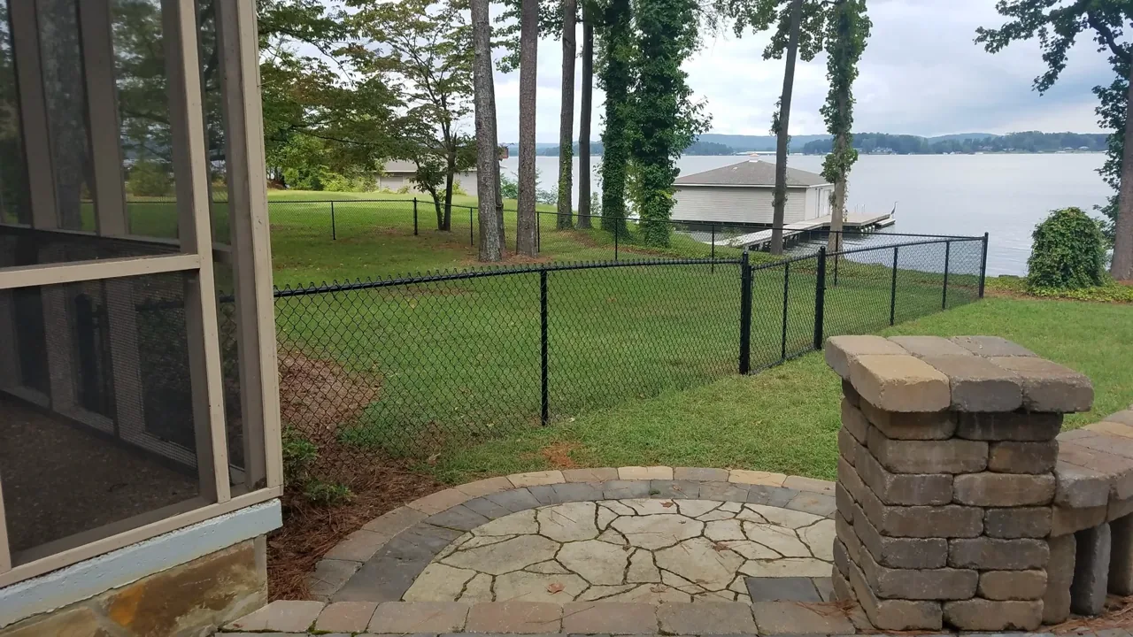 Black vinyl coated chain-link lakefront fence in Guntersville Alabama by Hooks Fence Company
