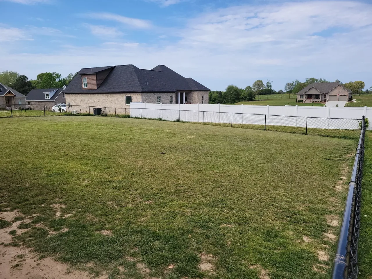 Black chain-link fence enclosing large residential yard in Ashville Alabama
