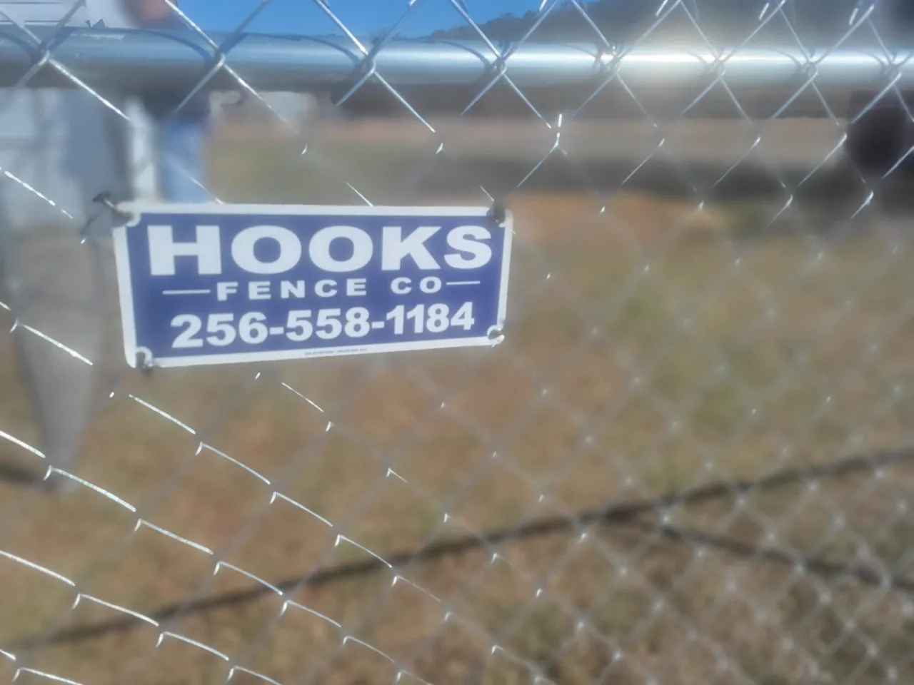 Hooks Fence Company sign on galvanized chain-link fence installed in Oneonta Alabama
