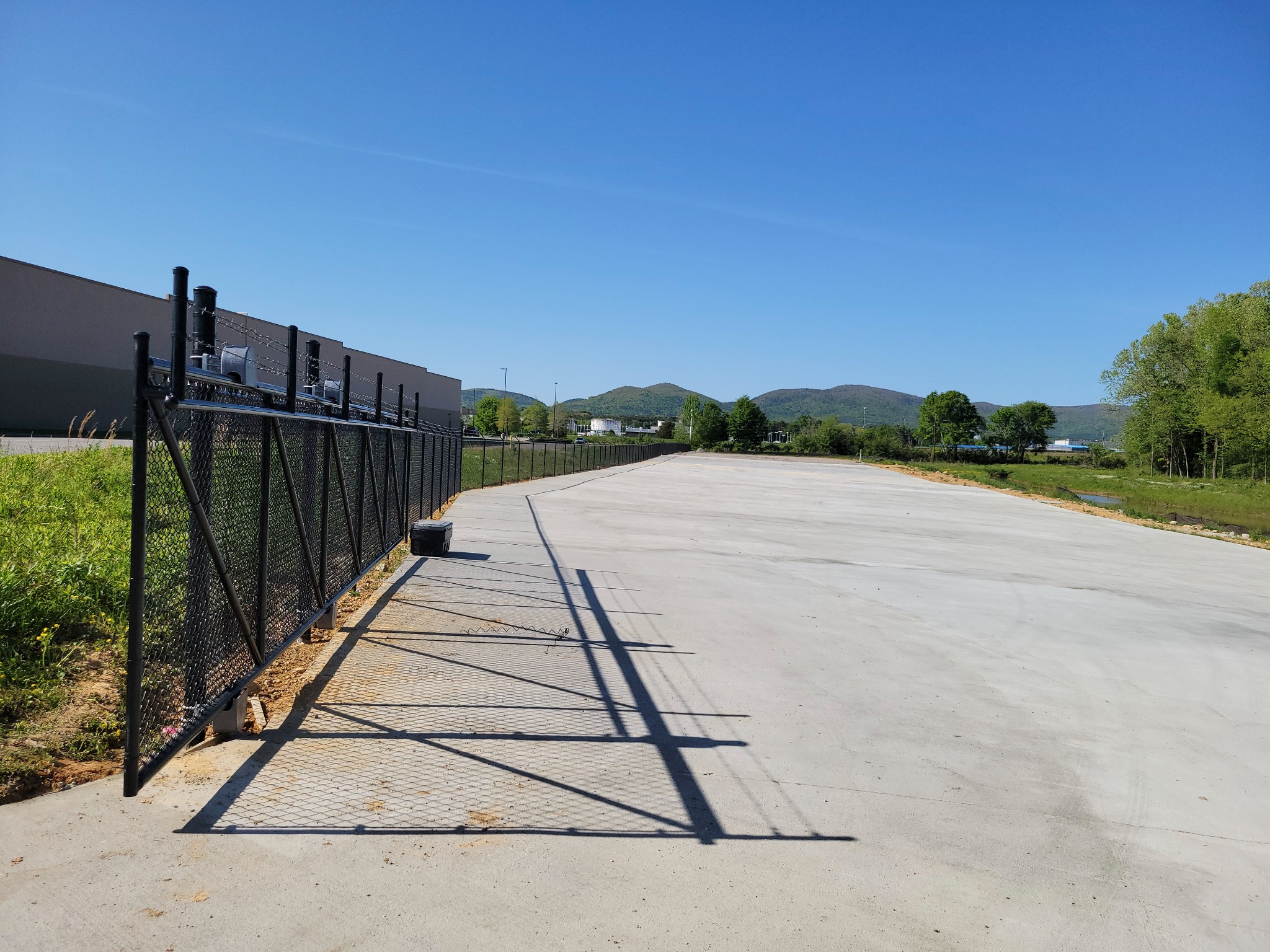 Black vinyl-coated industrial chain-link fence and cantilever gate installed by Hooks Fence Company in Oxford Alabama