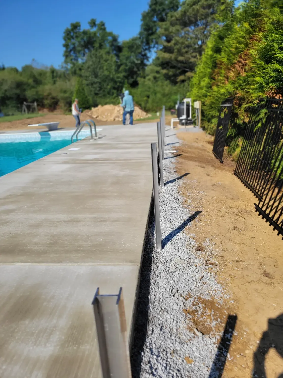 No-dig aluminum ornamental fence posts being installed beside a pool in Boaz, Alabama by Hooks Fence Company